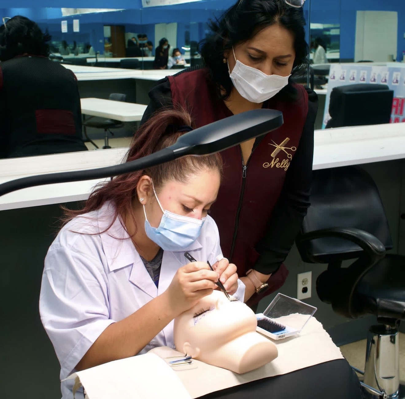 Instructor guiding a student through eyelash extension practice